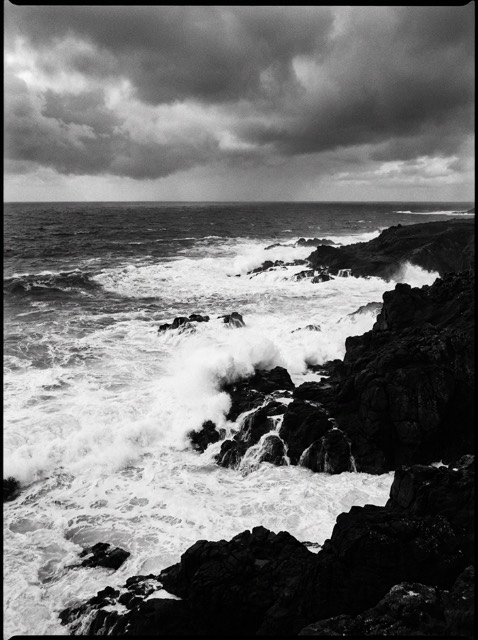 High contrast black and white waves breaking on dark coastal rock